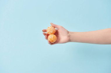 Kırpılan görünümünü soyulmuş mandalina el üzerinde izole mavi tutan kadın 