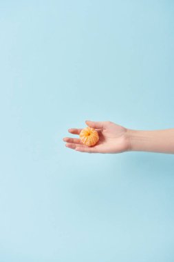Kırpılan görünümünü soyulmuş mandalina el üzerinde izole mavi tutan kadın 