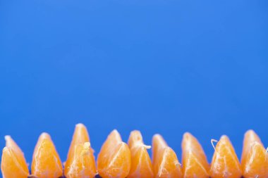 selective focus of organic peeled tangerine slices isolated on blue  clipart