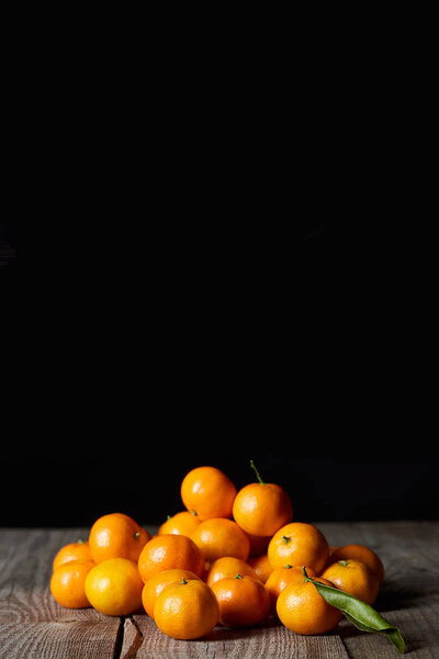 tasty orange tangerines with green leaf on wooden table isolated on black