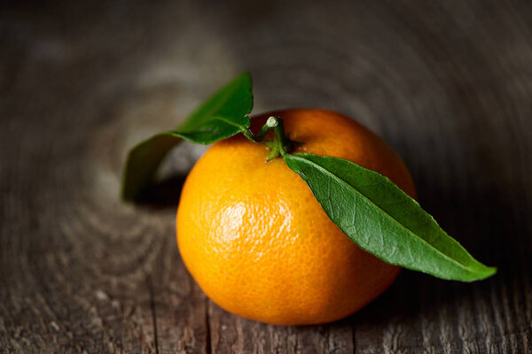 selective focus of tasty tangerine with green leaves on wooden table 