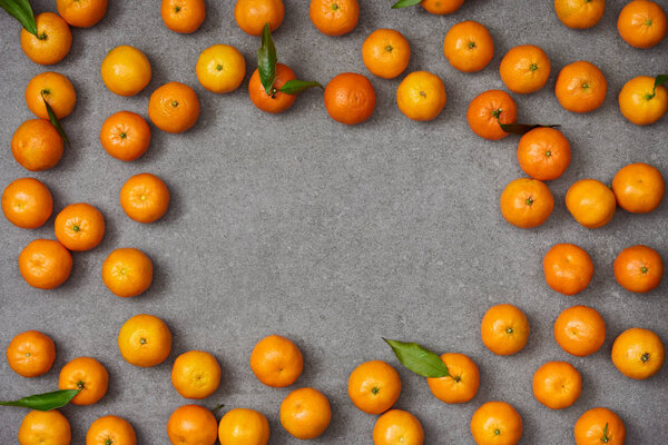 top view of sweet organic tangerines with green leaves on grey table