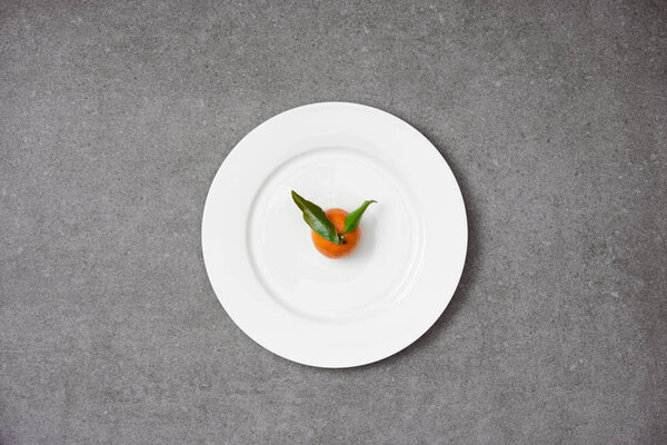top view of sweet organic tangerine with green leaves on white plate 