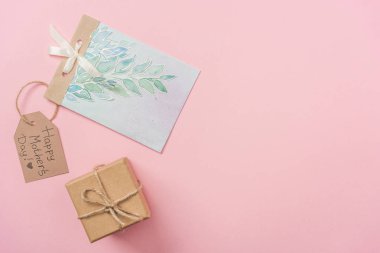 hediye kutusu, anneler günü tebrik kartı ve mutlu anneler günü tebrik metin pembe bir arka plan üzerinde ahşap etiketle 