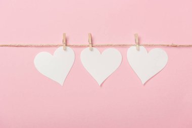 white paper hearts with coarse thread on pink background clipart