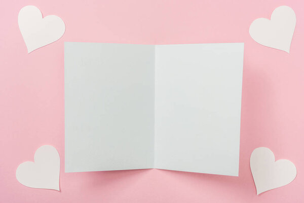 Открытки и белые бумажные сердечки на розовом фоне