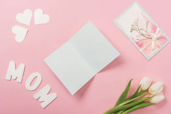 Kosong dan dihiasi ibu hari kartu ucapan, tulip putih, kertas hati dan kata ibu di latar belakang merah muda — Stok Gambar Kosong Dan Dihiasi Ibu Hari Kartu Ucapan Tulip Putih Kertas Stok Foto Bebas Royalti