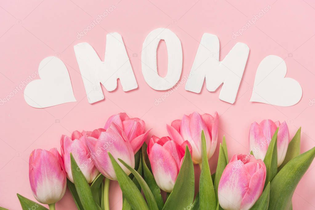 pink tulips, white paper word mom and paper hearts on pink background