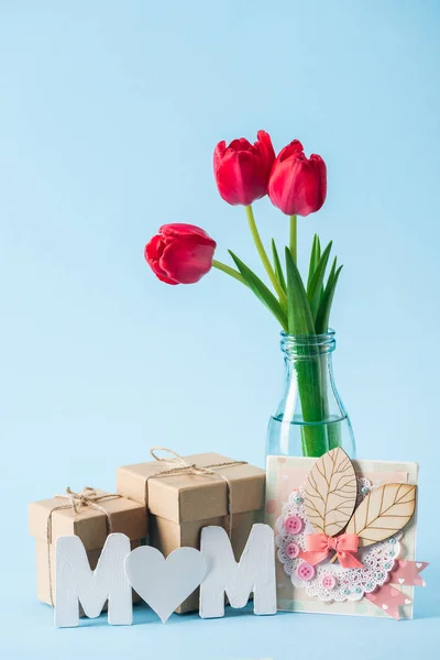 母亲天贺卡 礼品盒 红色郁金香花束和纸字妈妈与心形垃圾 在蓝色背景 — 图库照片