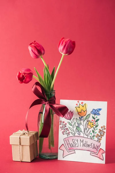 花束红色郁金香与红色缎子弓 快乐的母亲天贺卡和礼品盒在红色背景 — 图库照片