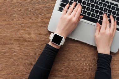 Laptop klavye ahşap zemin üzerine yazarak smartwatch ile kız görünümünü kırpılmış
