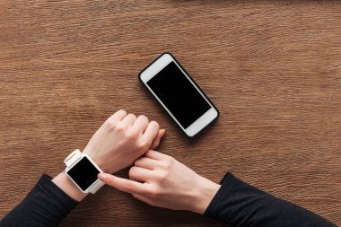 Kısmi ahşap arka plan boş ekran ile smartwatch kullanan kadın görünümünü