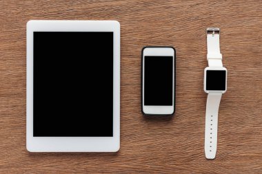 Ahşap arka plan üzerinde dijital tablet, smartphone ve smartwatch boş ekran ile üstten görünüm
