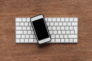 Ahşap arka plan üzerinde klavye ve smartphone ile boş perde üstten görünüm