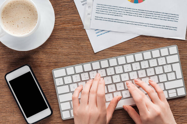 Обрезанный вид женщины, печатающей на клавиатуре на рабочем месте
