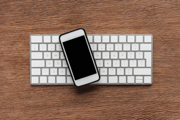 Ahşap arka plan üzerinde klavye ve smartphone ile boş perde üstten görünüm
