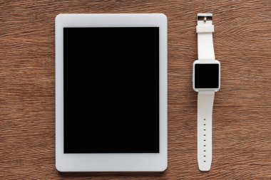 Ahşap arka plan üzerinde dijital tablet ve smartwatch boş ekran ile üstten görünüm