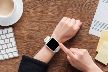Ahşap arka plan boş ekran ile smartwatch kullanan kadın görünümünü kırpılmış