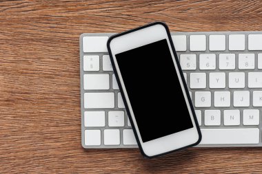 Ahşap arka plan üzerinde klavye ve smartphone ile boş perde üstten görünüm