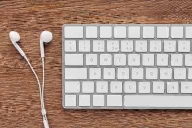 Ahşap arka plan üzerinde klavye ve kulaklık üstten görünüm