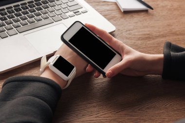 Kadın smartwatch, smartphone ve dizüstü bilgisayar ile görünümünü kırpılmış