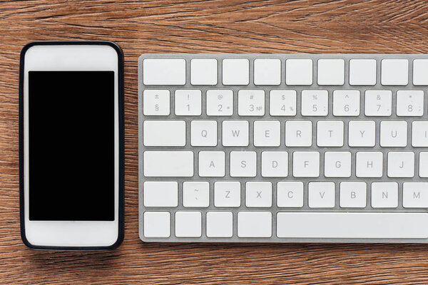 Вид сверху смартфона с экраном и клавиатурой на деревянном фоне
