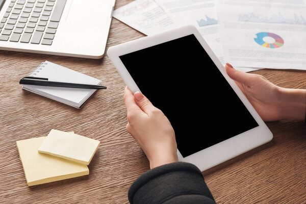 Partial view of woman posing with digital tablet with blank screen at workplace