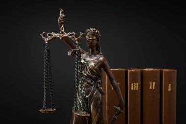 Adaletin terazisi ve birimler üzerinde siyah izole kahverengi kitap ile bronz heykelciği