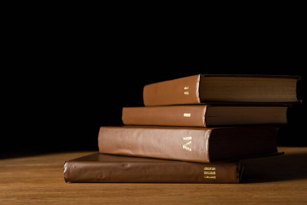 selective focus of brown leather books on wooden table isolated on black
