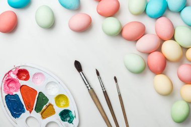 Üstten Görünüm pastel Paskalya yumurta renk paleti ve üzerinde beyaz izole Boya fırçaları 