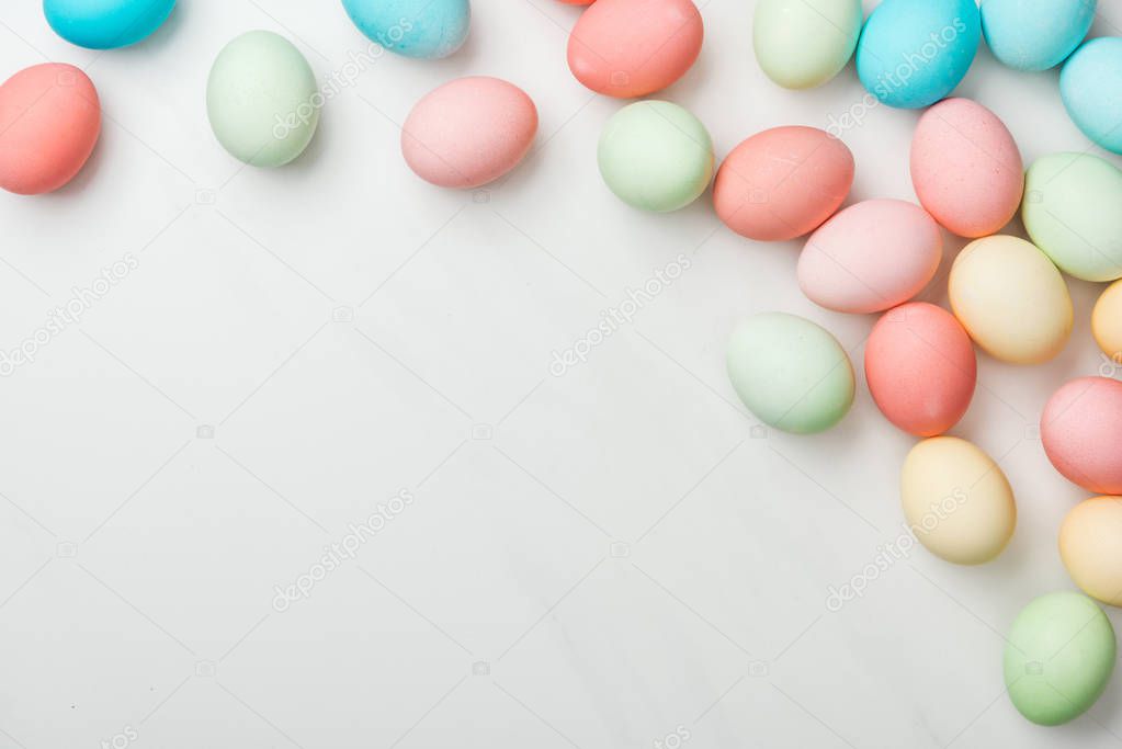 top view of scattered pastel easter eggs on white with copy space