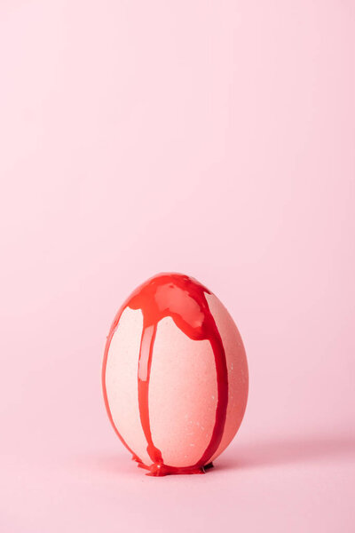 easter egg with red paint spills on pink with copy space