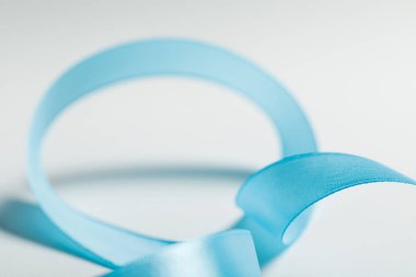 close up of curved blue satin ribbon on grey background clipart