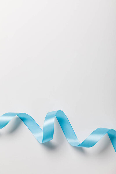 вид сверху на голубую волнистую атласную ленту на сером фоне с копировальным пространством
