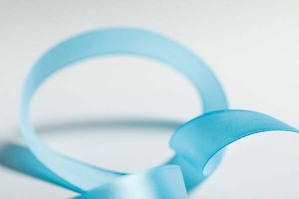 close up of curved blue satin ribbon on grey background