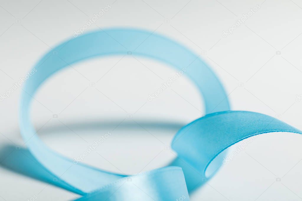 close up of curved blue satin ribbon on grey background
