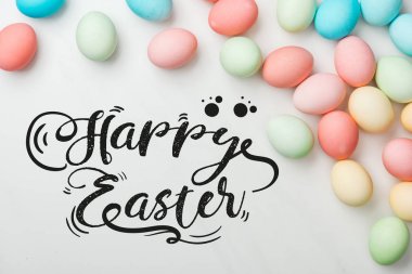 mutlu Paskalya siyah harflerle gri arka plan üzerinde çok renkli tavuk boyalı yumurta üst görünümü