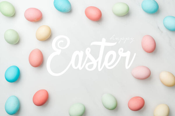 top view of multicolored chicken painted eggs on grey background with happy Easter white lettering