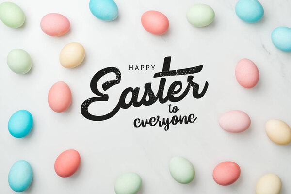 top view of multicolored chicken painted eggs on grey background with happy Easter to everyone lettering