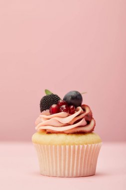 pembe yüzeyüzerinde krem, çilek ve garnet ile tatlı cupcake