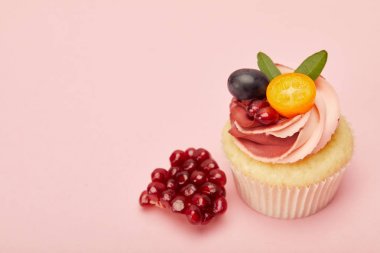 pembe yüzeyüzerinde krem ve garnet ile tatlı cupcake