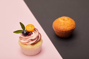 pembe ve siyah yüzeyüzerinde krema ve kek ile cupcake