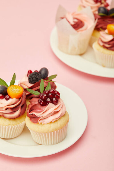 two plates with sweet cakes on pink surface