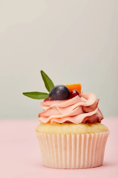 灰色に分離されたピンクの表面にクリームとフルーツとおいしいカップケーキ — ストック写真
