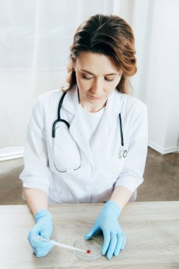 beyaz ceket ve lateks eldiven doktor kan örneği ile pipet tutan
