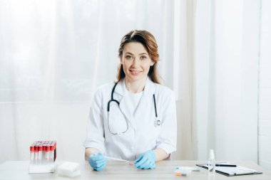 kan örneği ile pipet ve mikroskop slayt tutan gülümseyen doktor
