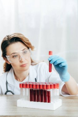 kan ile test tüpü tutan koruyucu gözlük konsantre doktor