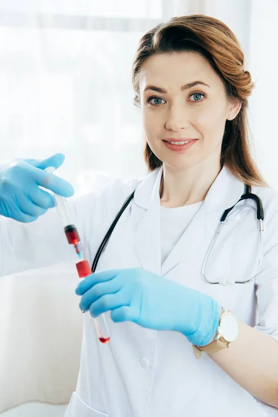 Sonriente Doctor Guantes Látex Sosteniendo Jeringa Con Muestra Sangre Probeta — Foto de Stock