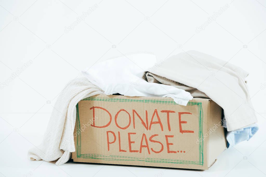 cardboard box with inscription and donated clothes on white