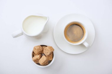 beyaz arka plan üzerinde süt ve kahverengi şeker yakın fincan lezzetli kahve üst görünümü